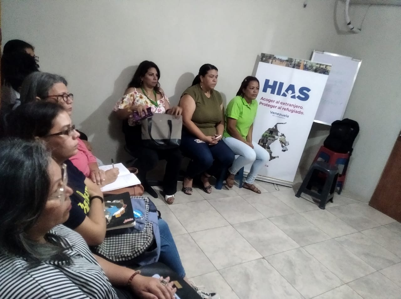 back view of woman wearing a backpack and beanie waiting to cross the road on a busy street at night in New York City, USA